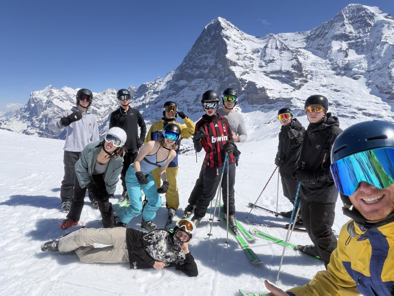 Group of youth on a sunny piste with the Eiger and Jungfrau in the background